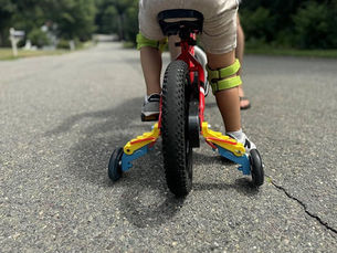 A child riding a bicycle along a road, enjoying a sunny day outdoors.