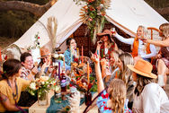 Women in western hats gathered around a colorful styled dinner table for a supper club event.