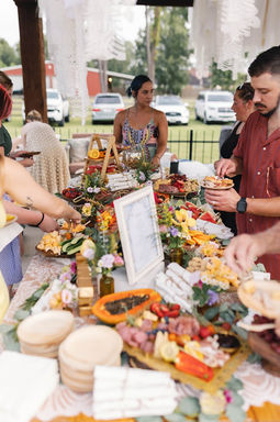 Wedding guests enjoying a colorful grazing table filled with fruit, cheese and appetizers.