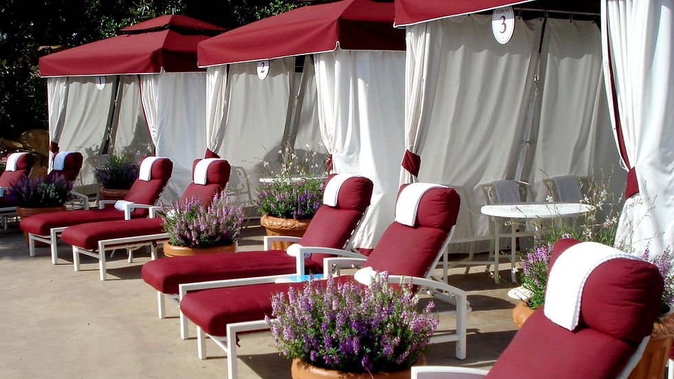 Close-up view of poolside lounge chairs with a family’s towels and drinks under a shaded cabana.