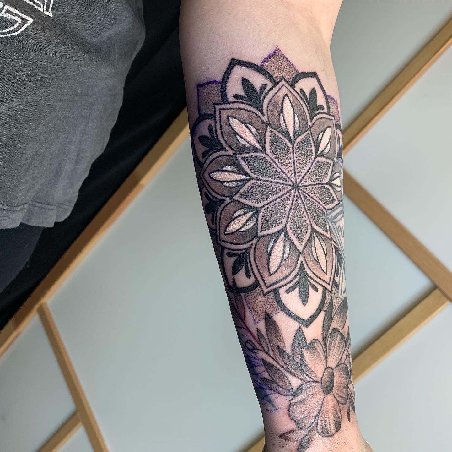 Black and grey forearm tattoo of a layered mandala with heavy stippled shading, published as the artists-hub tile linking to the Jesse Satyr profile under the alt text Mandala Tattoo