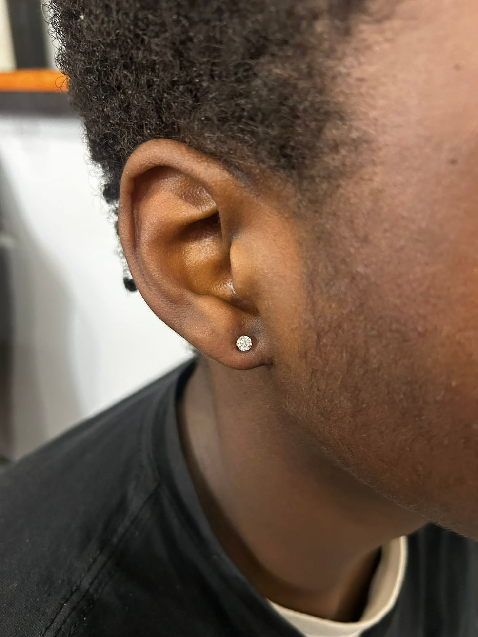 Close-up of a person's ear with a white stud earring and dark hair.
