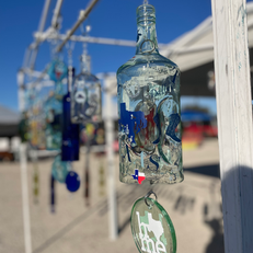 A group of glass bottles hang from a metal pole by wires.