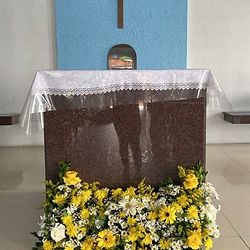 Altar com coroa de flores e crucifixo.