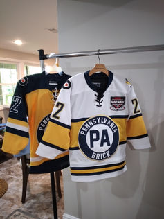 White, gold, and navy blue hockey jersey hanging on a rack
