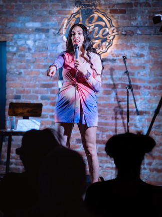 Comedian performing on stage with microphone at a Reno comedy event, photographed by Drel Studio