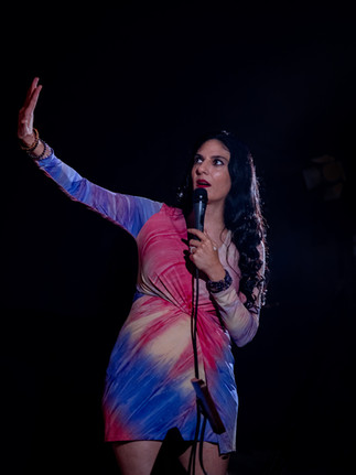Comedian performing on stage with microphone at a Reno comedy event, photographed by Drel Studio