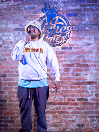 Comedian performing on stage with microphone at a Reno comedy event, photographed by Drel Studio