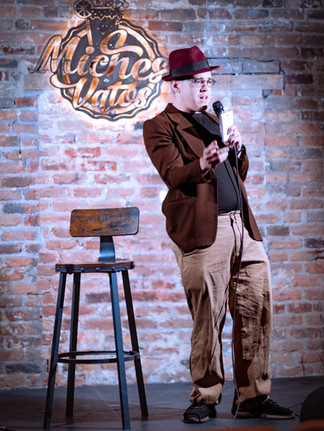 Comedian performing on stage with microphone at a Reno comedy event, photographed by Drel Studio