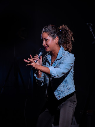 Comedian performing on stage with microphone at a Reno comedy event, photographed by Drel Studio