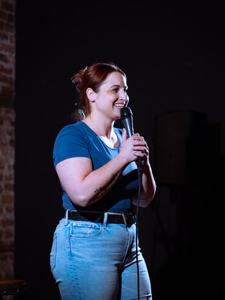 Comedian performing on stage with microphone at a Reno comedy event, photographed by Drel Studio