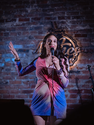Comedian performing on stage with microphone at a Reno comedy event, photographed by Drel Studio