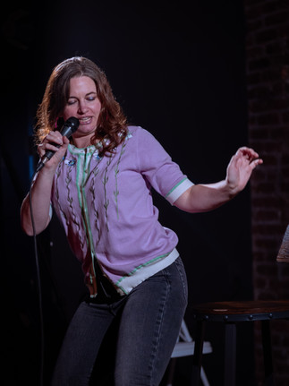 Comedian performing on stage with microphone at a Reno comedy event, photographed by Drel Studio