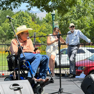man wearing a cowboy hat using a wheelchair and speaking on a stage