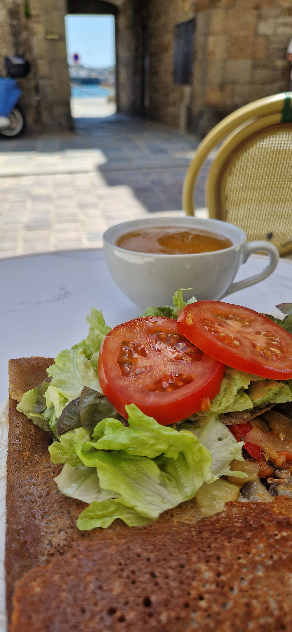une galette végétarienne en terrasse avec sa bolée de cidre et une vue sur la cale de Dinan