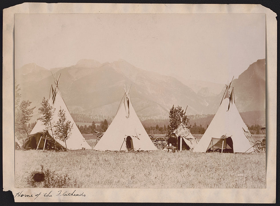 sepia tone old photo showing tipis with mountains in the background