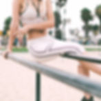 Woman in athletic wear doing rail exercises at a park with palm trees in the background.