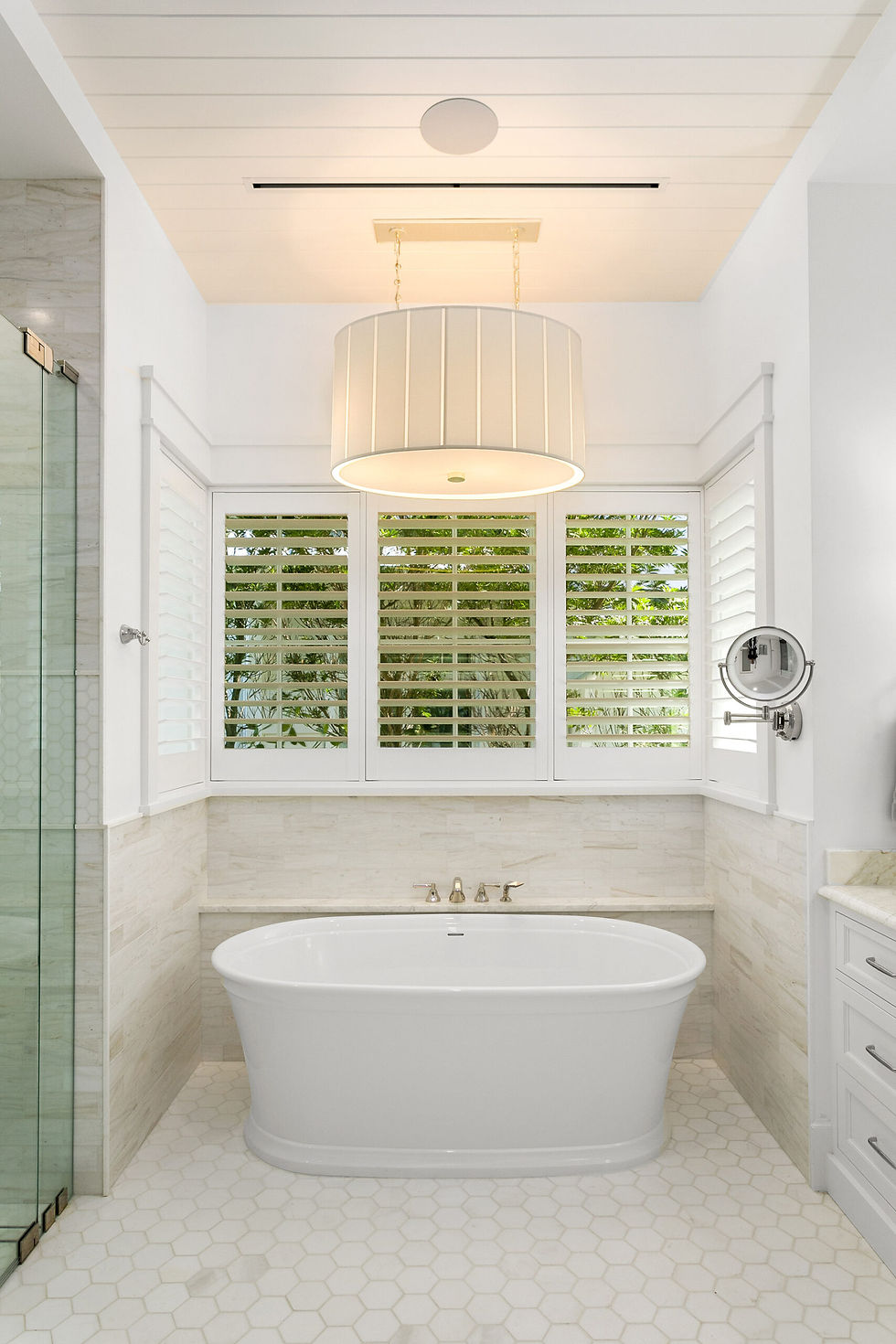 Stand alone white tub in warm lighted bathroom