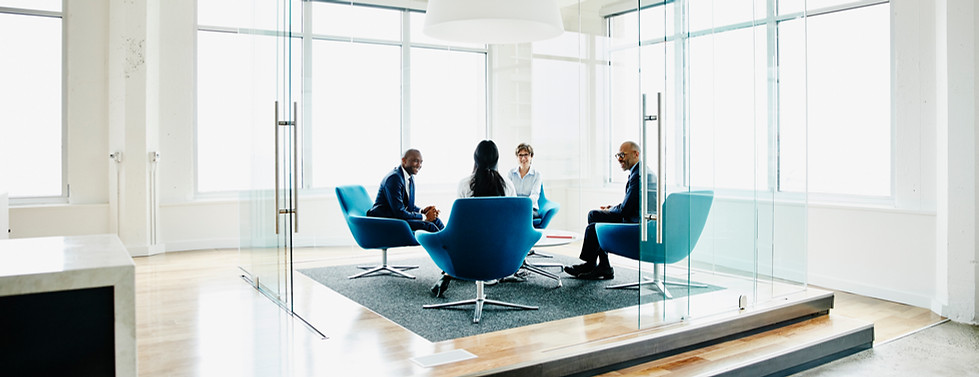 a group of people sitting on blue chairs in a glass office cubicle