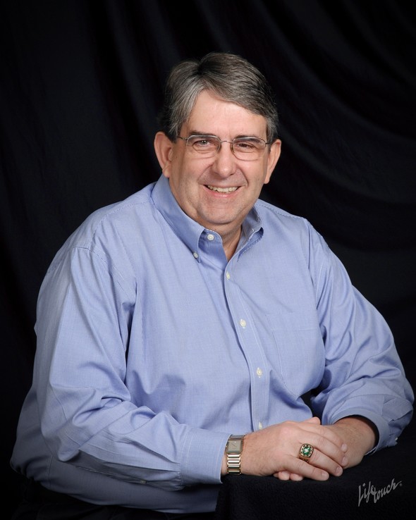 Professional portrait of Tom Till in a blue shirt.