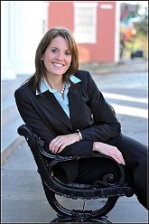 Smiling professional woman sitting on a black bench outdoors.