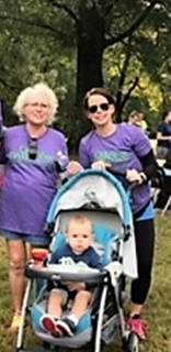 Two women in purple shirts with a child in a stroller