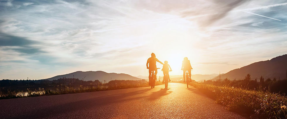 Family cycling into the sunset on a mountain road