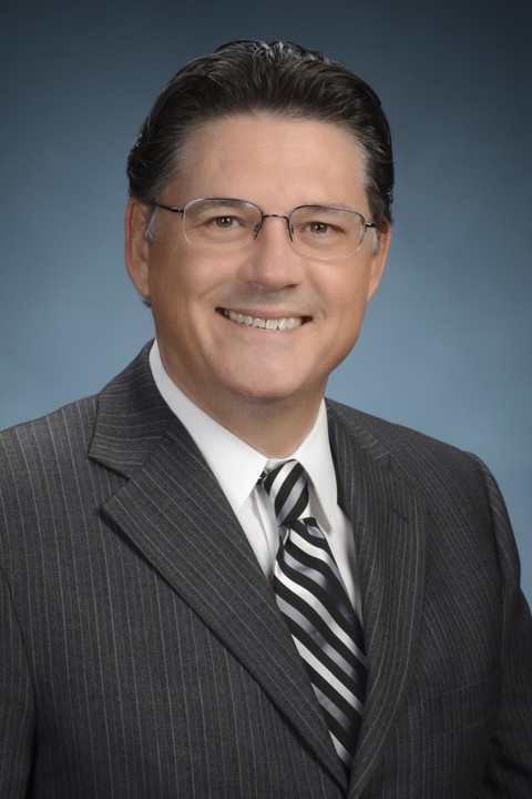 Smiling man in a pinstripe suit with a striped tie.