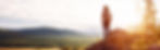 Hiker on mountain overlooking valley at sunset