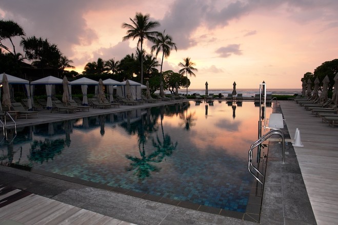 Luxury pool at sunset with palm trees and ocean views
