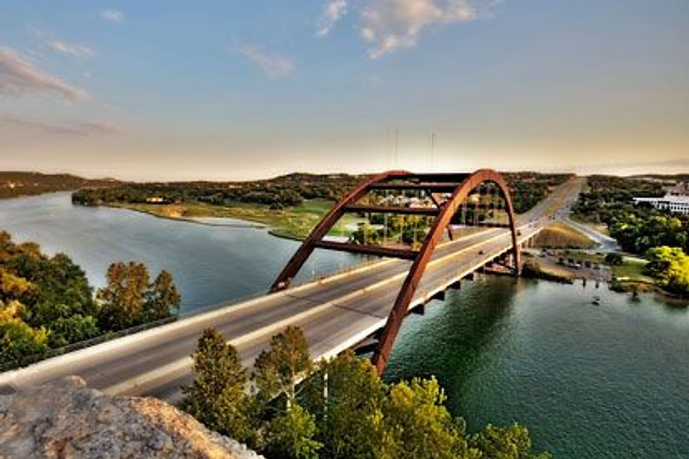 Steel arch bridge over a river at sunset