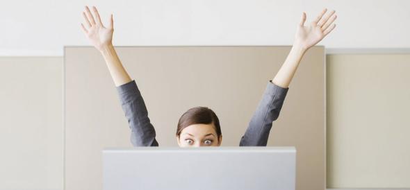 Professional woman cheering behind office cubicle wall