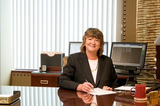 Professional woman smiling at a desk in a modern office.