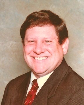 Smiling male associate in a suit and red tie.