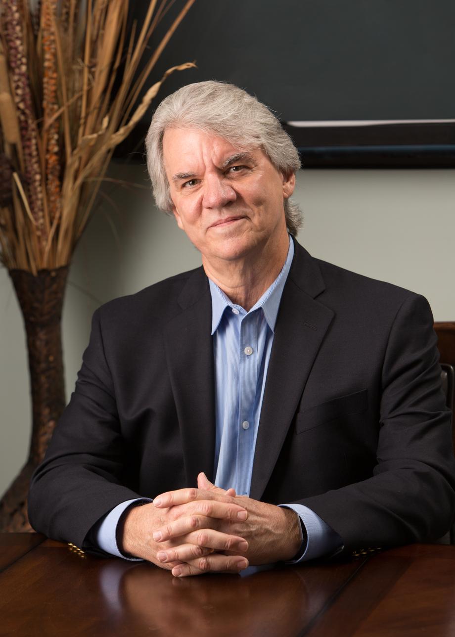 Professional man in a suit with hands clasped at a desk