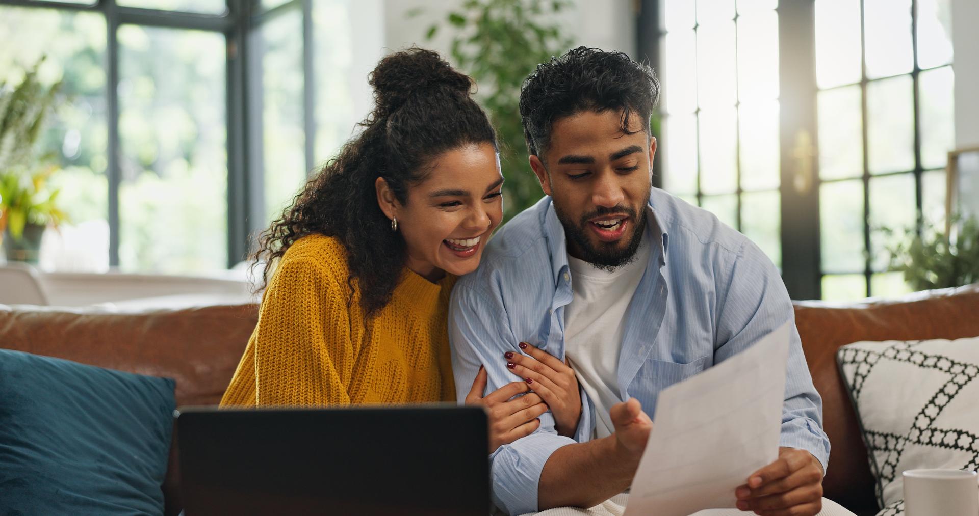 Couple reviewing documents together on a sofa at home.