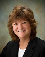 Smiling woman with brown hair in a black blazer.