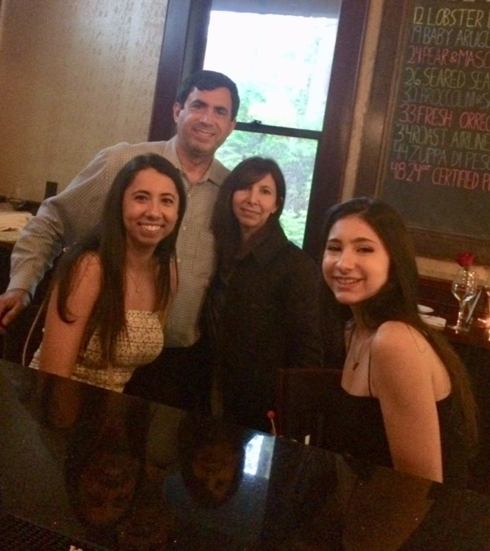 Family of four smiling at a restaurant table.