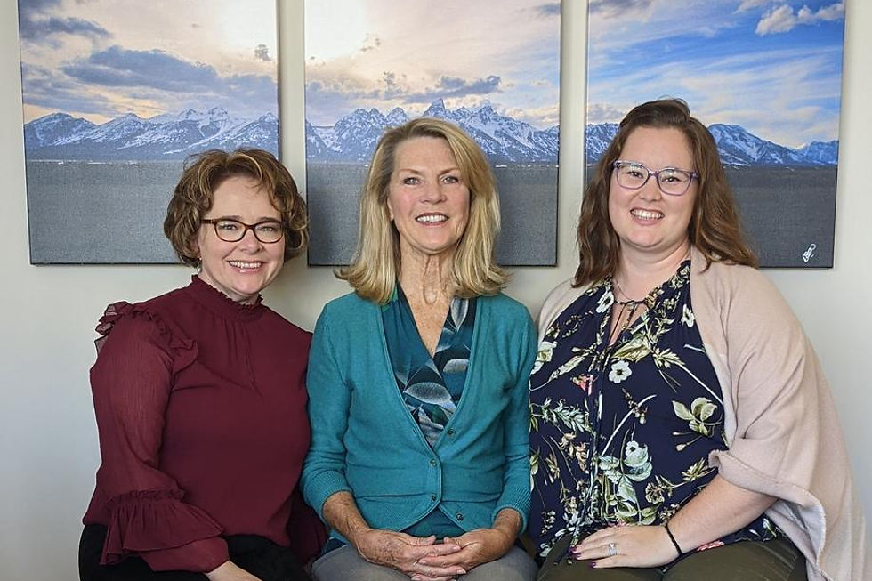 Three smiling professional women sitting together.