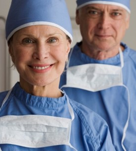 Two smiling surgeons in blue scrubs and caps.