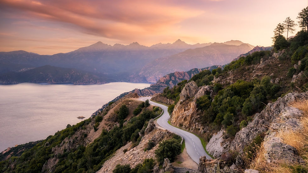 Winding road along a coastal mountain at sunset.