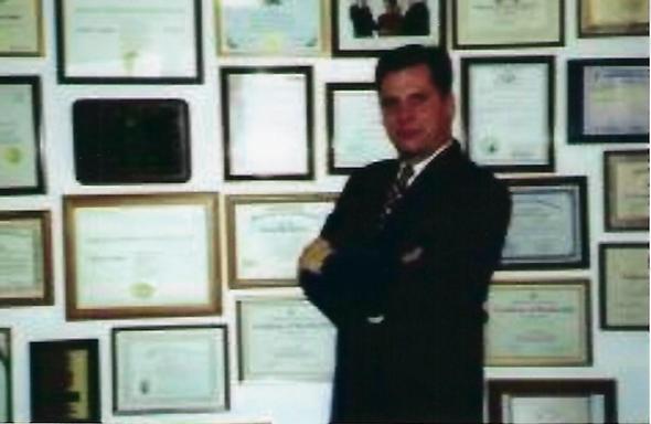 Professional associate in front of framed certificates