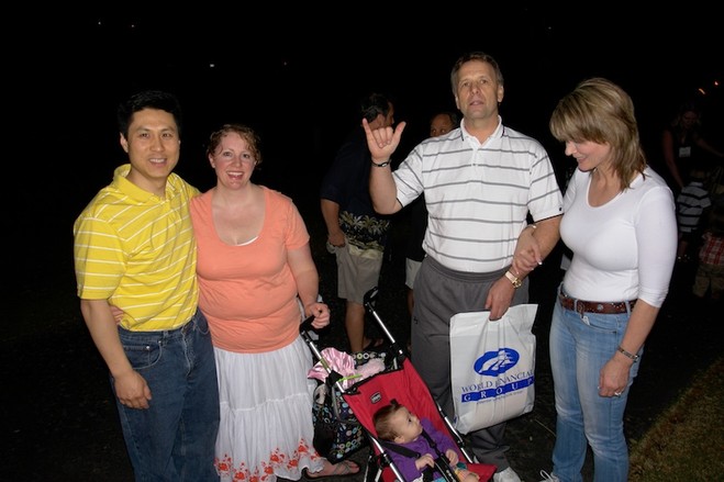 Group of four smiling adults with a baby in a stroller.