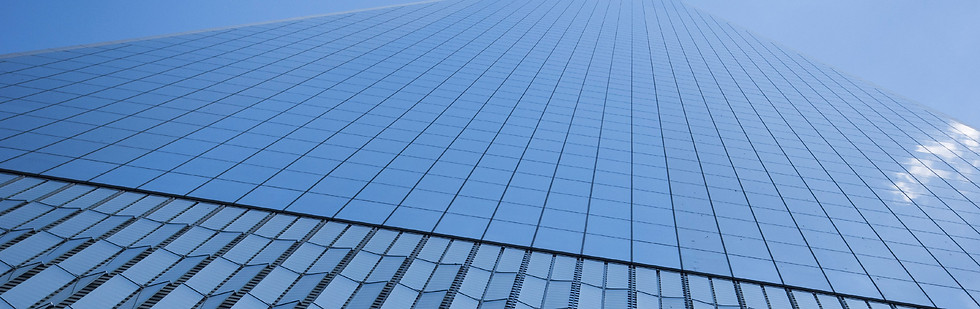 Low-angle view of a glass skyscraper against a blue sky