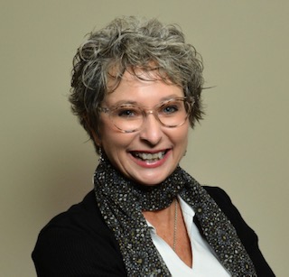 Smiling woman with short curly hair and glasses.