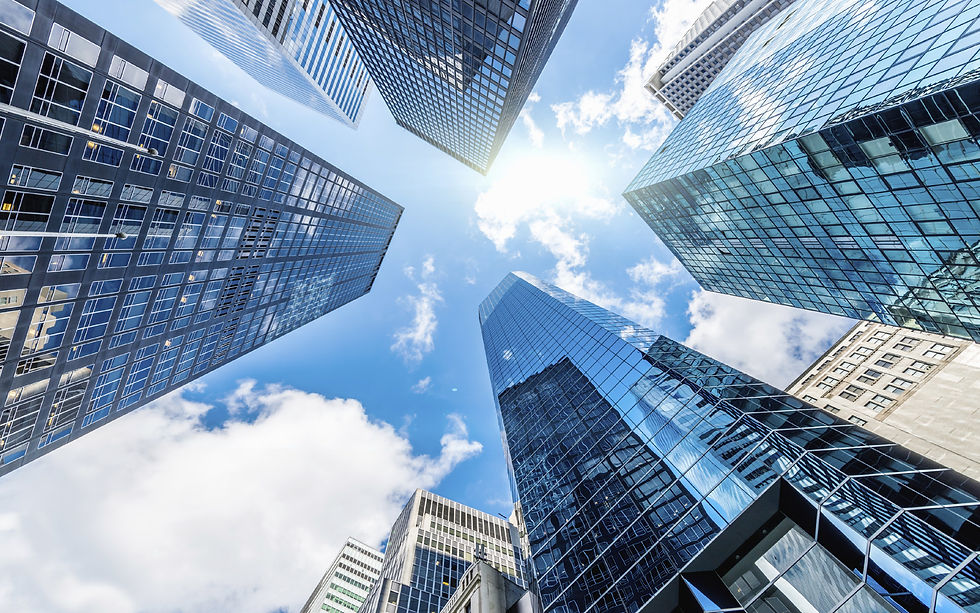 Looking up at modern glass skyscrapers and a sunny sky