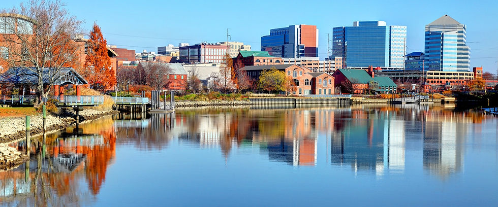 City skyline reflected in calm river water under blue sky