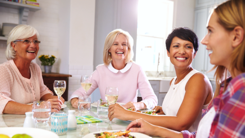 Women smiling and enjoying a meal at an educational workshop.