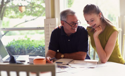 Older man and young girl smiling while reviewing paperwork.