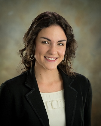 Smiling woman with brown hair in a black blazer.